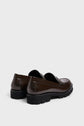 A pair of dark brown glossy loafers in mocassins cuir, with thick black semelle crantée soles, shown from the back and side angles against a plain light gray background for a style classique look.