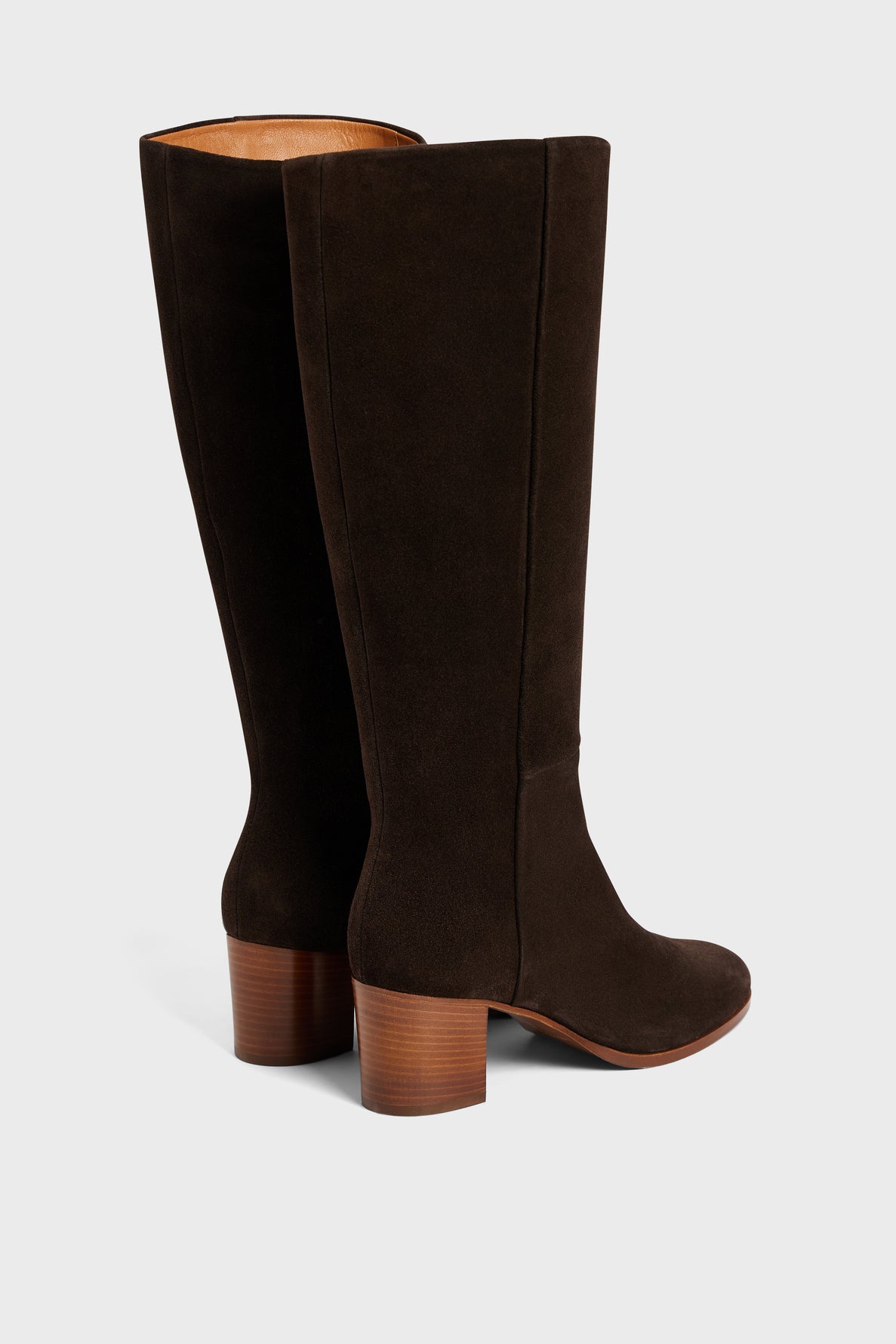 A pair of tall, dark brown bottes en cuir velours fabriquées en Italie with mid-height stacked wooden heels, shown against a plain light background. One boot stands upright while the other is angled behind it, highlighting the elegant silhouette of these bottes femme.
