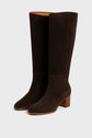 A pair of dark brown bottes femme en cuir velours, fabriquées en Italie, with a low, chunky wooden heel and almond-shaped toes, displayed against a plain light gray background.