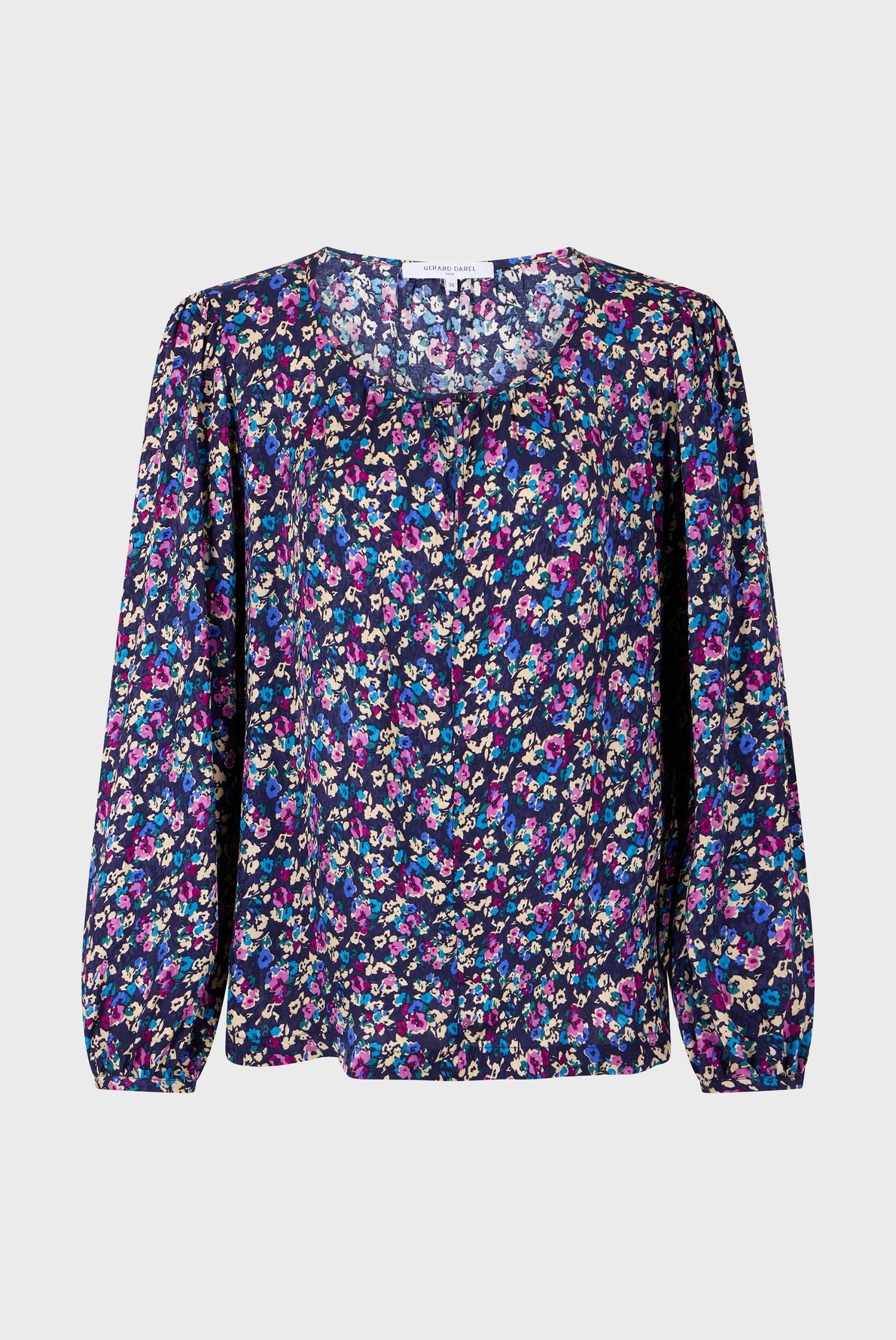 Long-sleeved blouse with a round neckline, featuring a colorful floral pattern on a dark background. The fabric appears lightweight with gathered cuffs and a buttoned front.