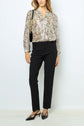 A woman stands against a white background wearing a long-sleeve floral blouse, black trousers, black slingback heels, and carrying a black shoulder bag with a gold chain strap.