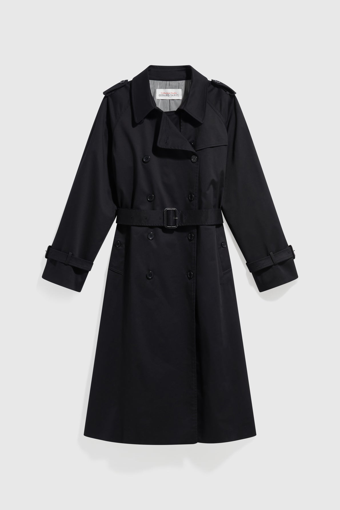 A black, double-breasted trench long coat in coton uni with a belt at the waist, buttoned front, and cuffed sleeves, designed as a manteau femme and displayed on a plain white background.