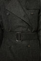 Close-up of a dark grey, double-breasted trench à chevron wool coat with black buttons and a matching fabric belt fastened at the waist. The fabric has a subtle herringbone pattern, making this manteau laine femme both elegant and timeless.