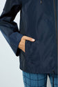 A person wearing a navy blue parka courte with capuche and blue plaid pants has their right hand in the jacket pocket.