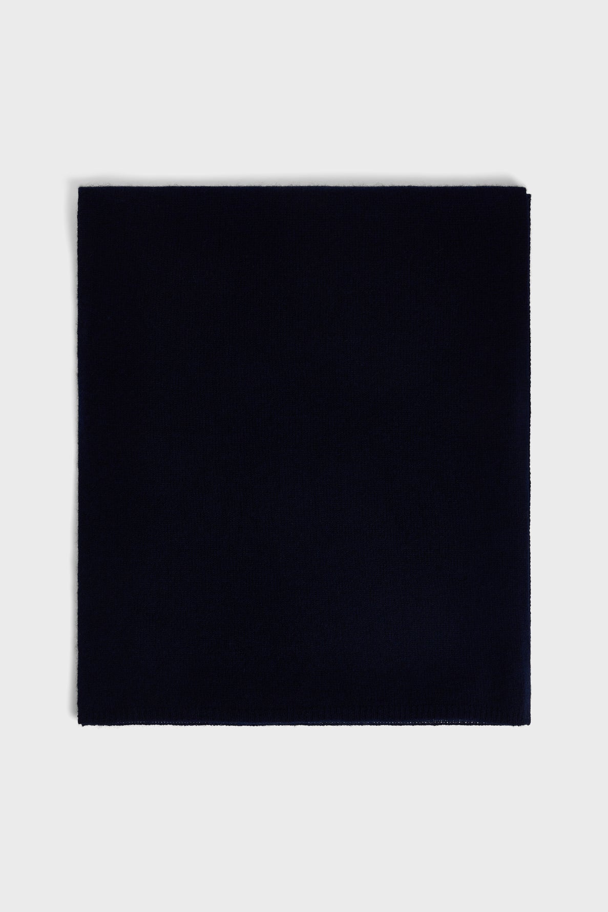 A square piece of dark navy blue fabric, reminiscent of a luxurious écharpe cachemire, is laid flat on a light gray background.