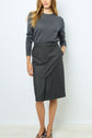 Woman wearing a long-sleeved dark gray sweater and a matching jupe droite motif Prince-de-galles, standing against a plain white background with her hand in her skirt pocket.