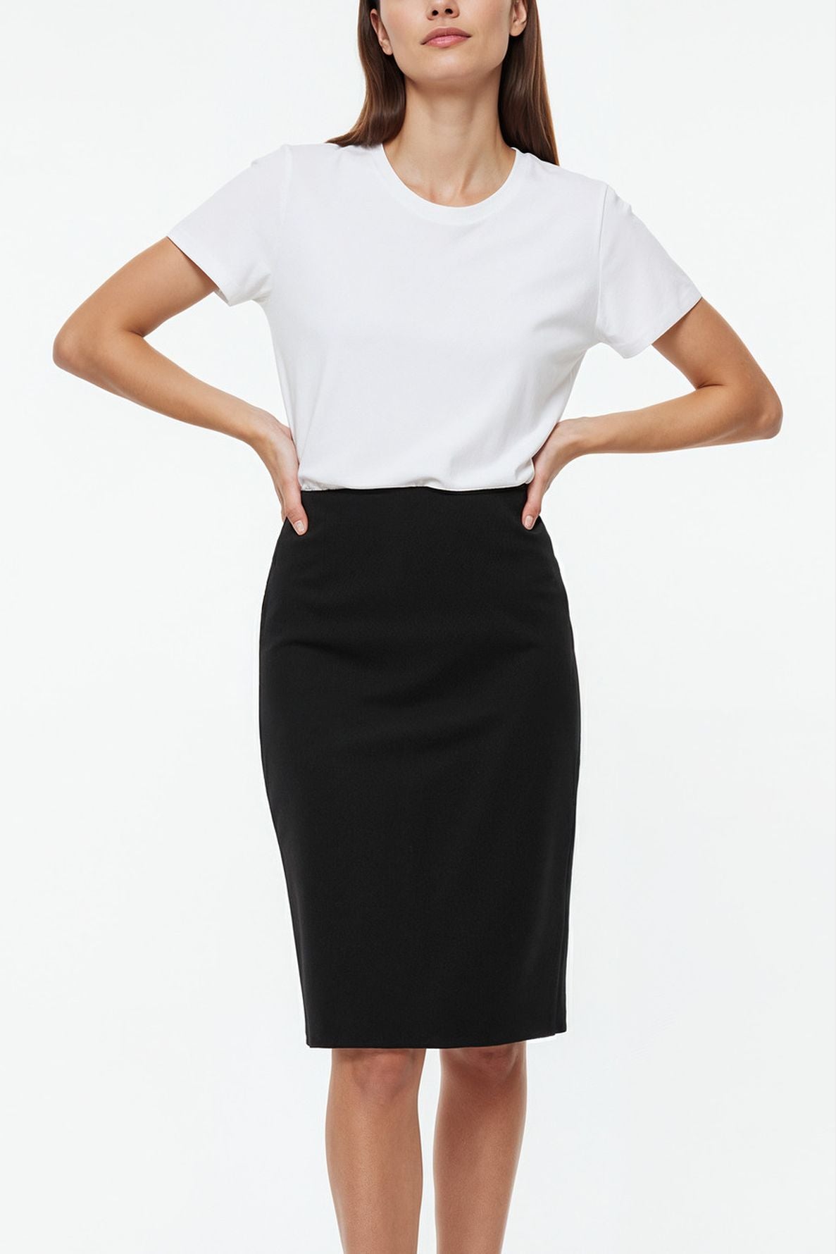 Woman wearing a plain white short-sleeve t-shirt tucked into a high-waisted, knee-length jupe noire en laine, standing with hands on hips against a white background.