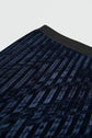 Close-up of a dark blue velours frappé pleated skirt with a black waistband, showing the textured fabric and subtle geometric pattern. This elegant jupe plissée falls at a midi length, highlighting both its luxurious material and refined style.