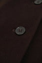 Close-up of a dark brown manteau laine featuring a black button sewn onto the fabric, with a visible buttonhole and textured surface detail.