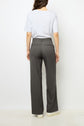 A woman stands facing away, wearing a light gray T-shirt and dark gray pantalon droit high-waisted pants with small white polka dots and subtle mini-strass embellishments, complemented by white shoes—all set against a plain white background for the collection Studio.