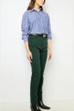 A person wearing a blue and white striped shirt, dark green pantalon coton with a coupe slim fit, a black belt, and black boots stands against a plain white background.