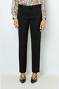 A person wearing black pantalon femme dress pants in a coupe ajustée fit, a floral blouse with long sleeves, and black pointed-toe heels standing against a plain white background.
