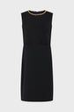 Sleeveless black dress with a fitted waist and a gold chain detail around the neckline, this petite robe noire embodies effortless elegance and modern style. Displayed on a plain white background.