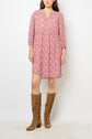 A person wearing a pink floral robe courte in airy crêpe georgette and knee-high tan suede boots stands against a plain white background.