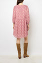 A woman stands facing away, wearing a pink motif floral robe courte with three-quarter sleeves crafted from crêpe georgette, paired with brown knee-high suede boots, against a white background.