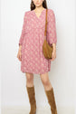 Woman wearing a pink floral crêpe georgette robe courte with long sleeves, brown knee-high suede boots, and a tan shoulder bag, standing against a plain white background.