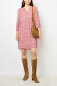 A woman wearing a pink motif floral crêpe georgette robe courte, knee-high tan suede boots, and carrying a brown shoulder bag stands against a plain white background.