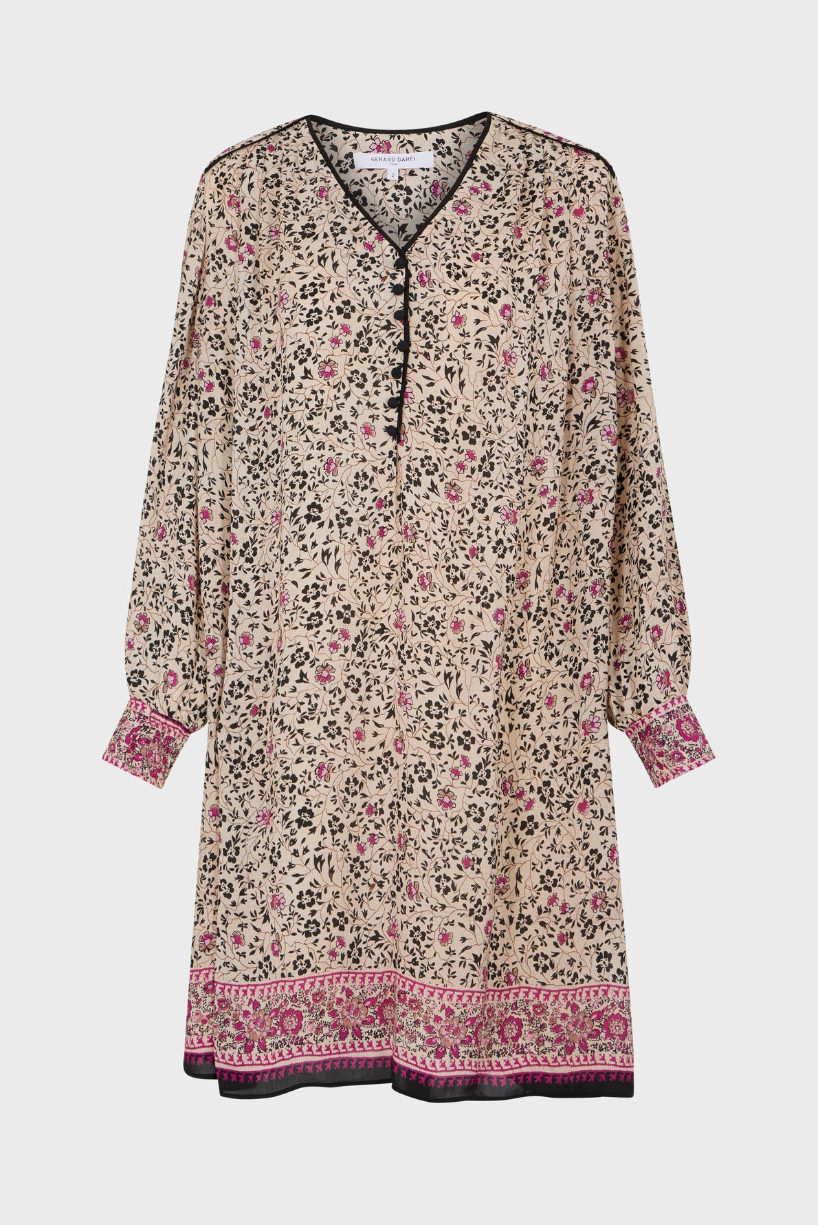 A long-sleeved beige tunic dress with a black, pink, and white imprimé floral pattern, black buttons, and pink decorative borders on the cuffs and hem.