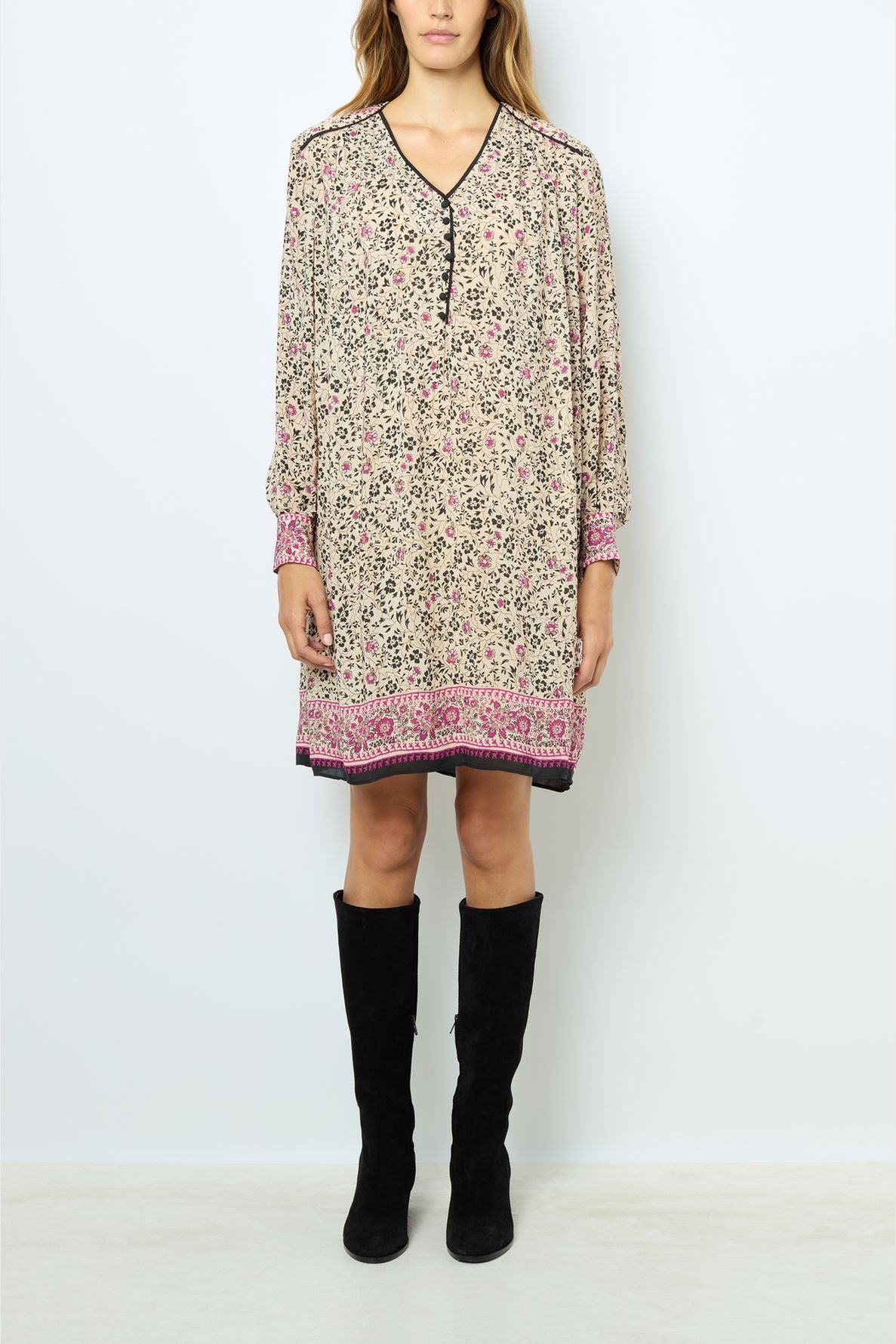Woman wearing a loose, robe courte à imprimé floral with manches longues and pink borders, paired with black knee-high boots, standing against a plain white background.