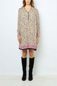 Woman wearing a loose, robe courte à imprimé floral with manches longues and pink borders, paired with black knee-high boots, standing against a plain white background.