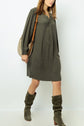 Woman wearing a loose, long-sleeve robe kaki with subtle jacquard patterns, knee-high slouchy suede boots, and carrying a taupe shoulder bag. The background is plain white.