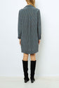 A person wearing a long-sleeve, motif géométrique robe droite femme and knee-high black boots stands facing away from the camera against a plain white background.