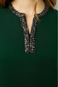 A close-up of a person wearing a robe courte in vert profond, featuring a V-neckline embellished with black and silver beading.
