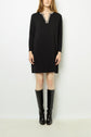 A woman stands against a white background wearing a black robe courte à manches longues with a patterned V-neckline adorned with col strass, paired with knee-high black boots.