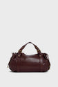 A dark brown maroquinerie Darel leather duffel bag with gold hardware, two handles, and side drawstring details crafted from cuir délicat, displayed against a light gray background.