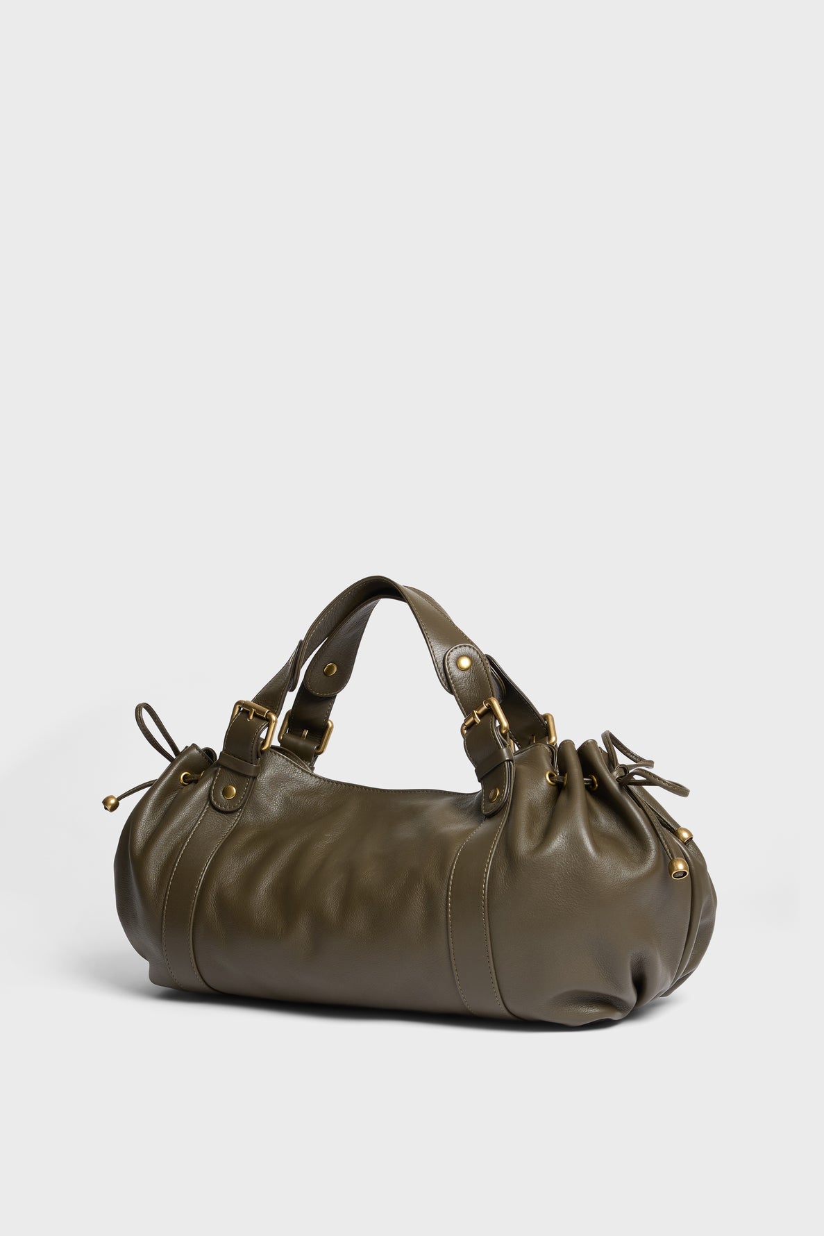 Olive green leather sac à main with gold hardware, two short handles, and gathered drawstring details on both ends, placed on a plain light background. This elegant piece showcases cuir délicat and the refined craftsmanship typical of maroquinerie Darel.