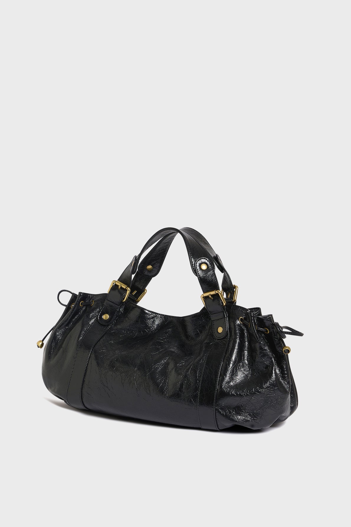 A black cuir froissé leather handbag with gold hardware, double handles, and a slouchy, rounded shape is displayed against a plain white background—a timeless piece of maroquinerie Darel craftsmanship.