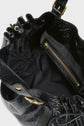 Open black leather handbag with gold hardware, showing a zippered inner pocket and drawstring closure against a white background—a stylish sac à main crafted in cuir froissé, echoing the timeless elegance of maroquinerie Darel.