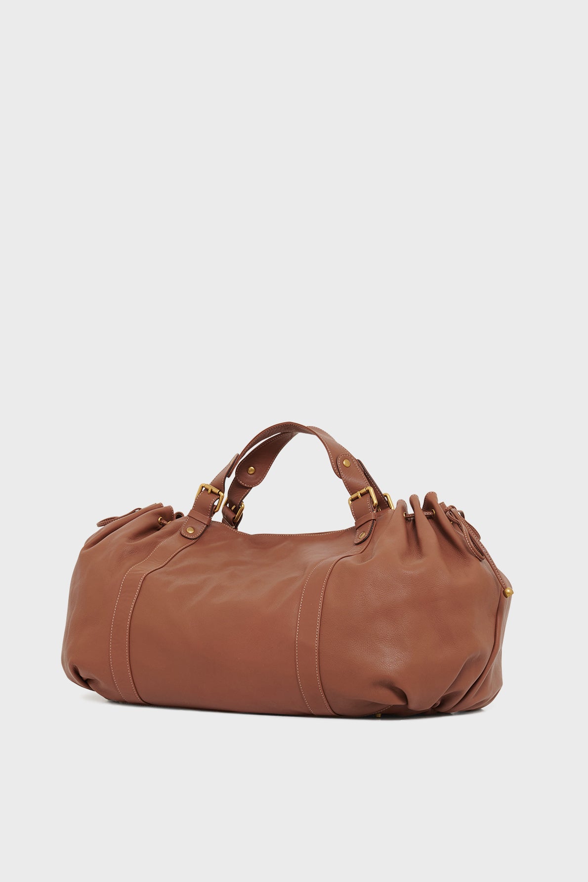 Brown leather sac à main with gold-tone hardware, short double handles, and gathered sides crafted from cuir délicat, displayed against a plain white background.
