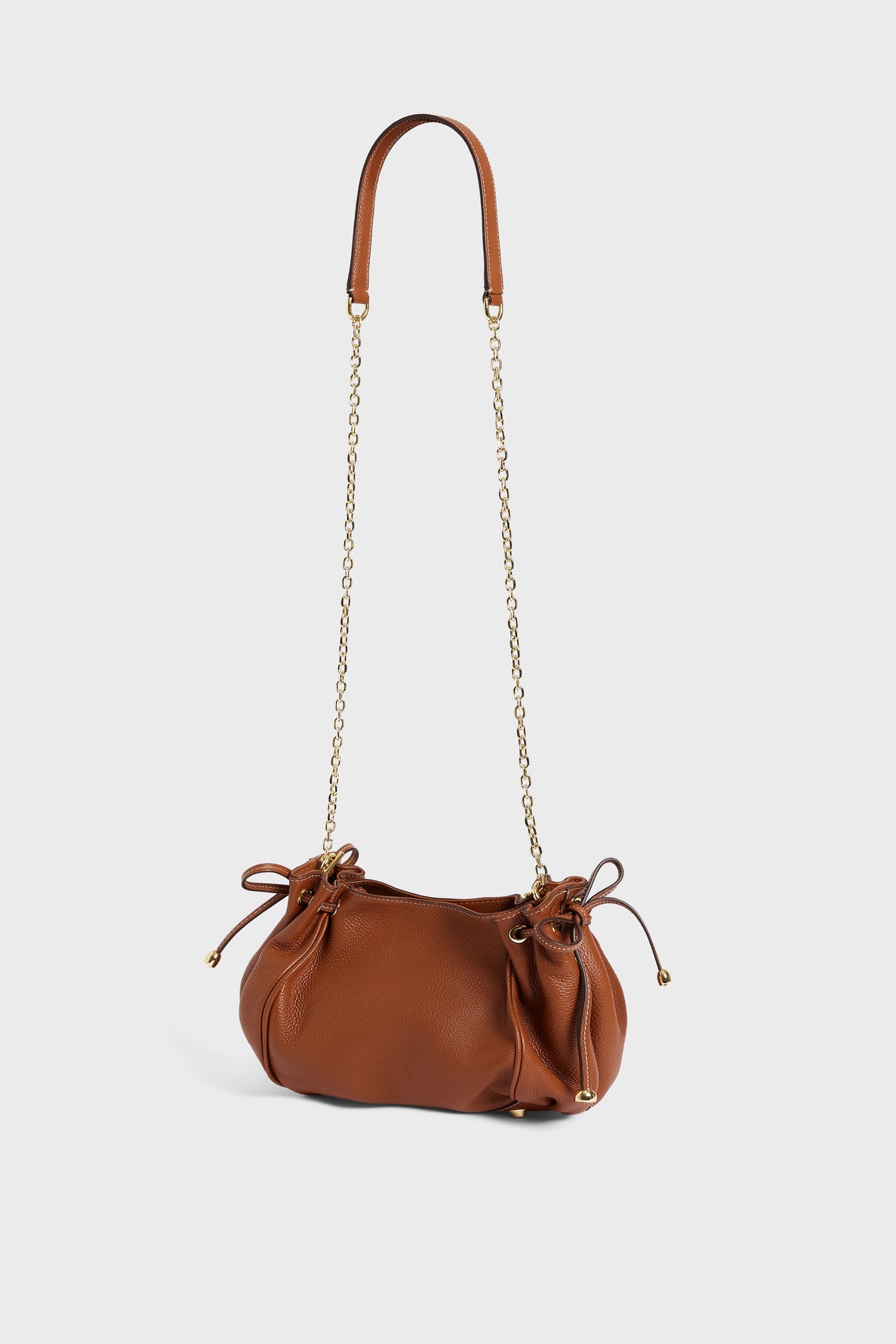 Brown leather handbag with gold chain strap and leather handles, featuring drawstring sides and a soft, gathered shape in cuir grainé, photographed on a plain white background. This elegant sac bandoulière from Gerard Darel combines classic design with modern sophistication.