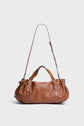 A Gerard Darel sac à main in brown cuir grainé, featuring two short handles and a long adjustable shoulder strap, complemented by gold hardware and a minimalist design, displayed against a plain light background.