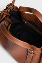 A close-up of an open Gerard Darel sac à main in brown cuir grainé leather with gold hardware, showing a spacious black fabric-lined interior and a zippered pocket inside.