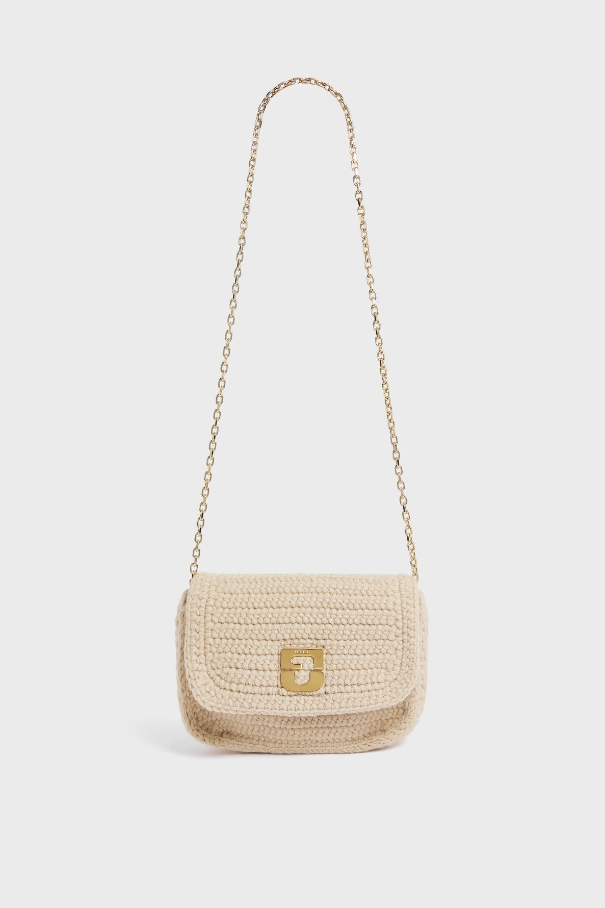 A small beige besace en tricot de laine, crocheted by hand with a gold chain strap and a gold clasp on the front, is displayed against a plain white background.