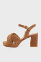 A tan suede block-heeled sandal with a crisscross toe strap and an ankle strap featuring a small round buckle. Expertly fabriquées en Italie, these sandales à talons larges are crafted from cuir velours beige. The heel is thick and the sole has a slight platform.