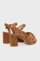 Pair of brown cuir velours beige high-heeled sandals à talons larges, fabriquées en Italie, featuring thick heels, crisscross straps at the front, and adjustable ankle straps with gold buckles, displayed on a plain white background.