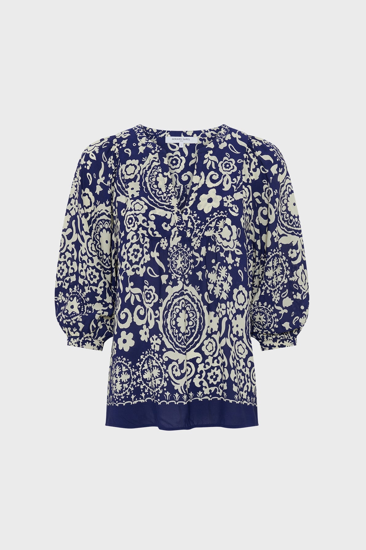 A navy blue blouse fluide with a light motif floral and paisley print, featuring a round neckline, ruffled front, and three-quarter puff sleeves. The background is plain white.