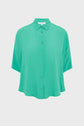 A loose-fitting, short-sleeve, button-up green chemise oversize with a collar, displayed against a plain white background.