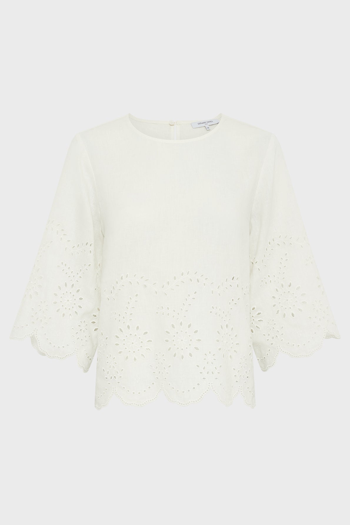 White blouse with elbow-length, flared sleeves and scalloped edges. The fabric features an eyelet floral pattern along the hem and sleeves. The blouse has a round neckline and a simple, elegant design.