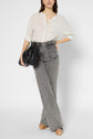 A person wearing a white pinstripe blouse, gray high-waisted wide-leg jeans, tan platform sandals, and holding a black handbag stands against a plain white background.
