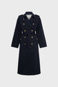 A long, navy blue manteau femme, designed in classic trench long style with double-breasted front, features elegant boutons dorés, a waist belt, and shoulder epaulets—all displayed on a plain light gray background.