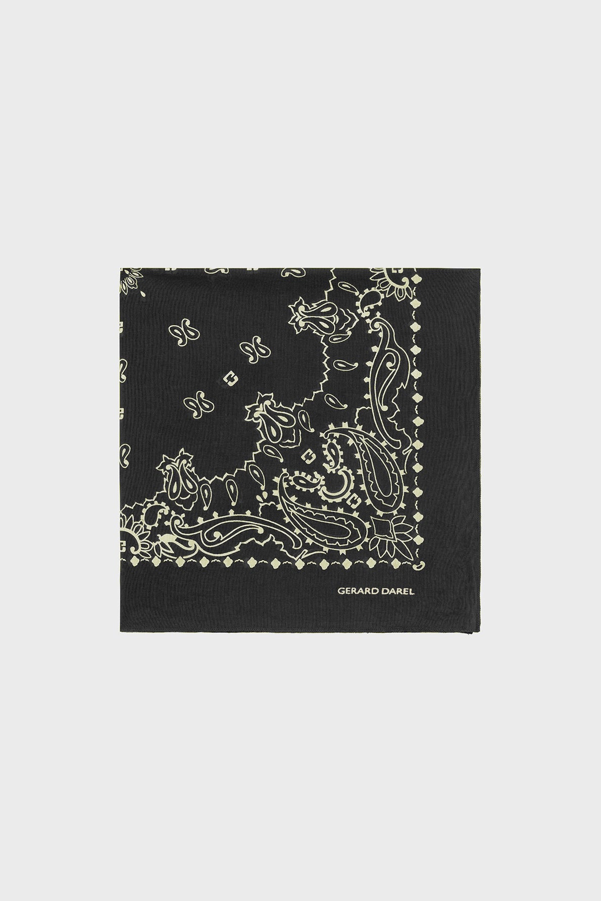 A folded black bandana coton with a beige paisley and dotted border pattern, featuring classic bandana motifs géométriques and the brand name Gerard Darel printed in white on one corner, placed on a plain white background.