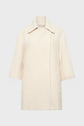 A cream-colored, textured manteau coton laine with a wide collar, three-quarter sleeves, and two front pockets, featuring a subtle motif chevrons and displayed on a plain light gray background.