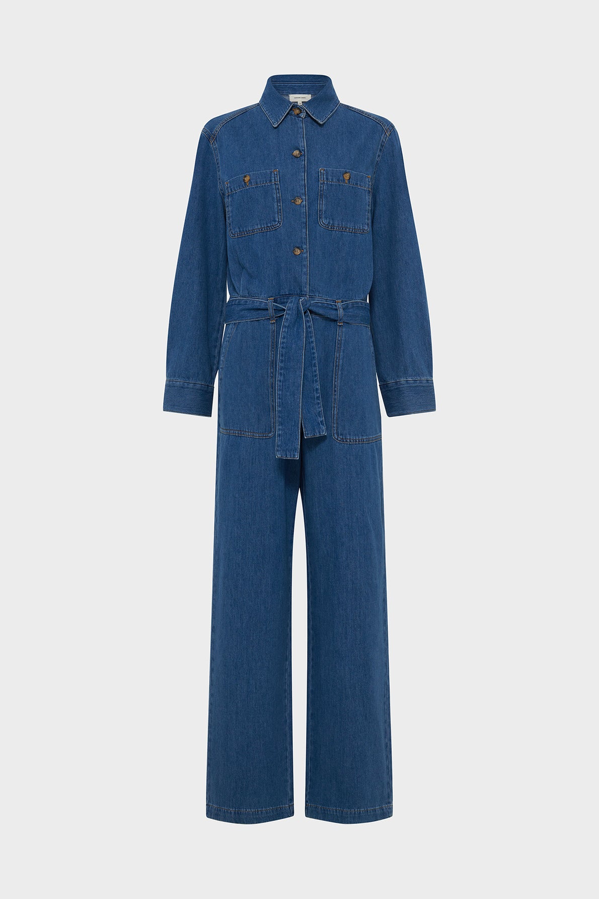 Blue denim long-sleeve jumpsuit with a collar, button-down front, two chest pockets, and a ceinture amovible at the waist. This elegant denim femme combinaison en jean features wide-leg pants and is displayed against a plain white background.