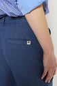 A person wearing a blue and white striped shirt and blue pantalon large en lin et lyocell with a small white rectangular label above the back pocket.