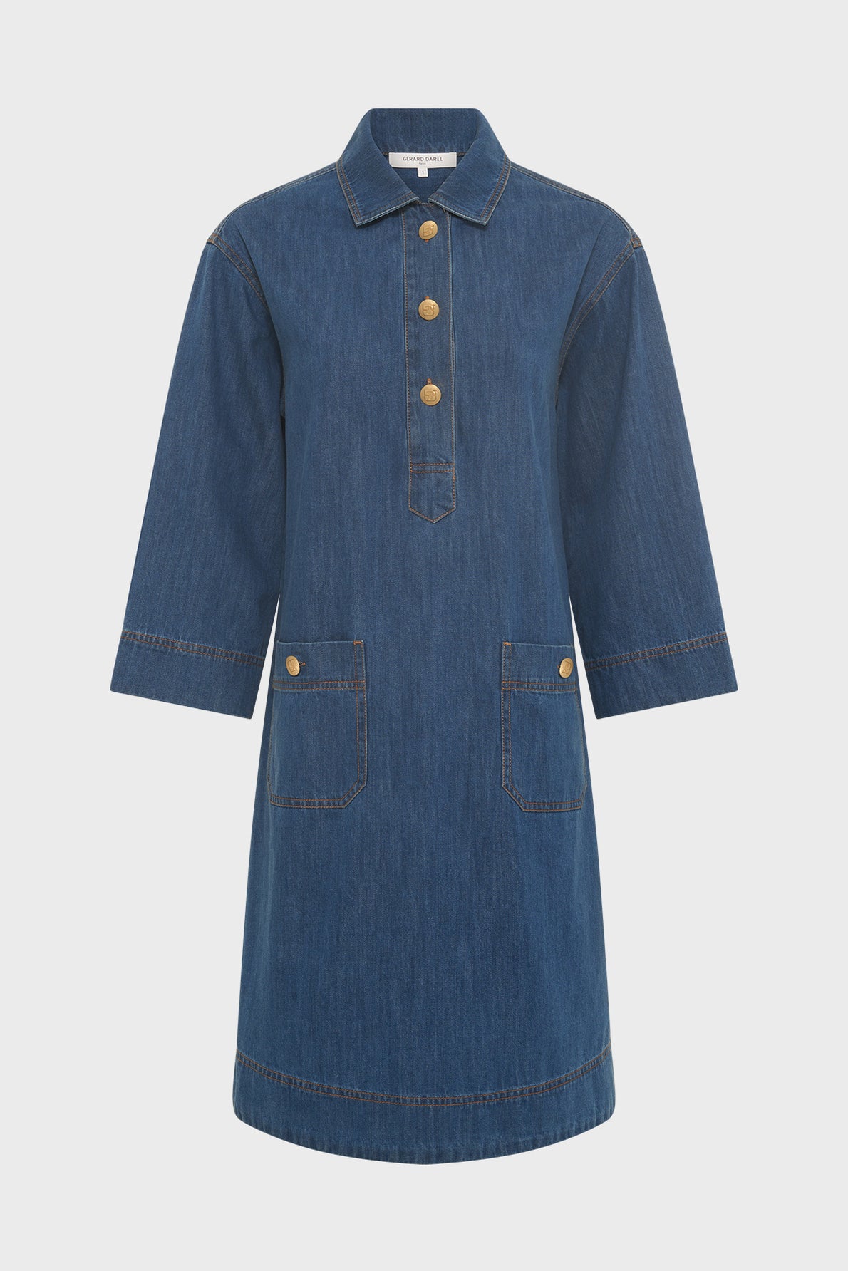 A knee-length denim dress with three-quarter sleeves, gold buttons on the front placket, two front pockets with gold buttons, and a classic shirt collar.