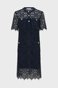 Short-sleeved navy lace dress with a collar, button placket, four front pockets, and gold buttons. The dress features a floral lace pattern and scalloped hem.